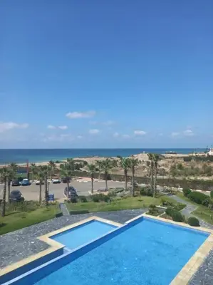 a swimming pool with the ocean in the background at Appartement Casablanca in Dar Bouazza