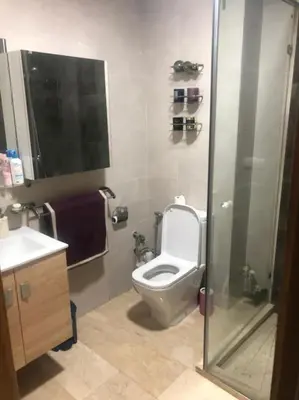 a bathroom with a toilet and a glass shower stall at Appartement Casablanca in Dar Bouazza
