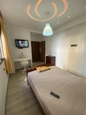 a bedroom with a bed with a remote control on it at Appartement avec suite parentale in Mohammedia