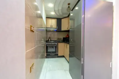 a kitchen with stainless steel appliances and wooden cabinets at Laura Residence in Bouznika