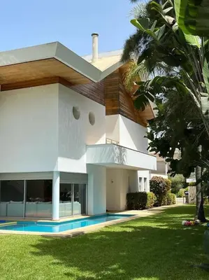 a large white house with a palm tree in front of it at Belle Villa à Bouznika plage - Golf Bouzbay in Bouznika