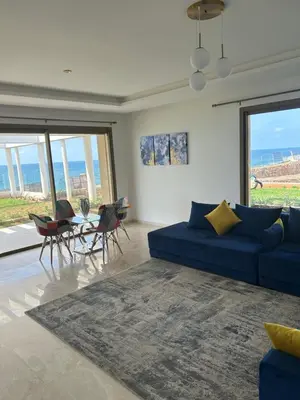 a living room with a blue couch and a table and chairs at Le Carrousel Appartement in front of the see in Rabat
