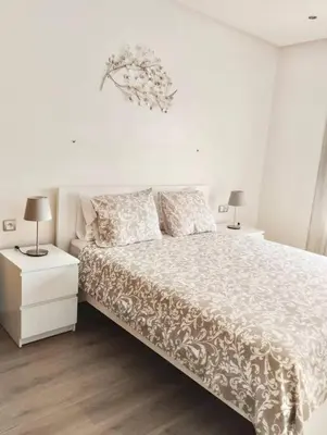 a white bedroom with a bed and two lamps at Appartement Cozy au Triangle d’or in Casablanca