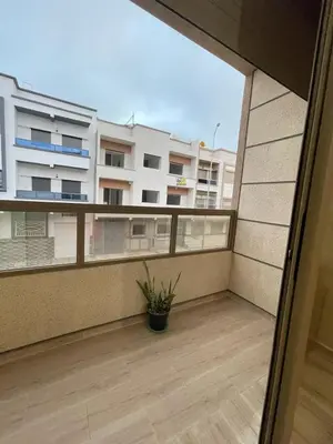 a balcony with a potted plant and a building at Chez Soad in Bouznika