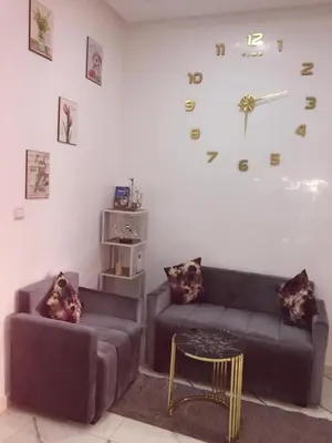 a living room with a couch and a clock on the wall at Airport M V chambre stay in Deroua
