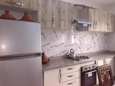 a white kitchen with a refrigerator and a stove at Airport M V chambre stay in Deroua