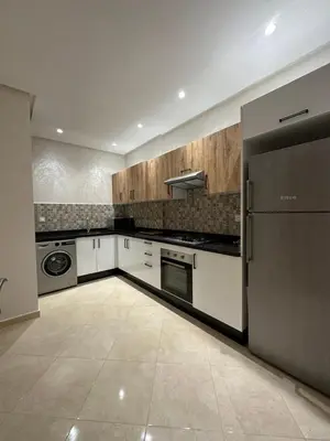 a large kitchen with white cabinets and a refrigerator at Apparemment de luxe Bouznika in Bouznika