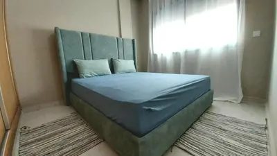 a bed with a headboard in a room with a window at appartement moderne proche aéroport in Derroua