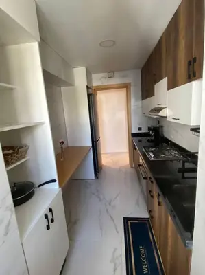 a kitchen with white cabinets and a black counter top at Belle appartement à découvrir in El Harhoura