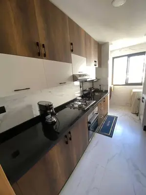 a kitchen with wooden cabinets and a black counter top at Belle appartement à découvrir in El Harhoura