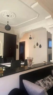 a dining room with a table with chairs and a mirror at Naj'Appart TEMARA WIFAK CALME SITUÉ PRÉS DE LA GARE FERROVIAIRE 4 MIN A PIED in Temara