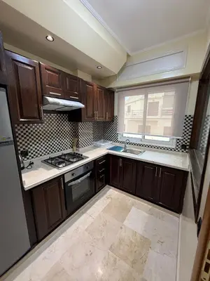 a kitchen with wooden cabinets and a stove top oven at Appart Hôtel Oleandro in Casablanca