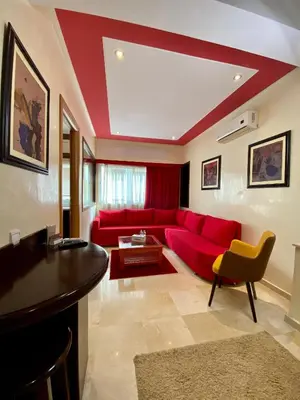 a living room with a red couch and a table at Appart Hôtel Oleandro in Casablanca
