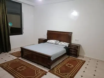 a bedroom with a large wooden bed and two rugs at Villa à la décoration marocaine in Rabat