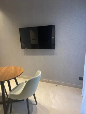 a table and a chair and a television on a wall at Magic Appartement Luxury Gauthier 04 in Casablanca