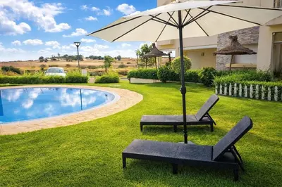 two chairs and an umbrella next to a pool at Appart Residence Haut Standing in Bouznika