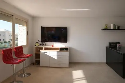 a living room with a tv and two red chairs at Appart Residence Haut Standing in Bouznika