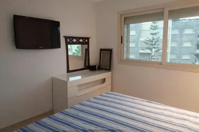 a bedroom with a bed and a tv on the wall at Appart Residence Haut Standing in Bouznika