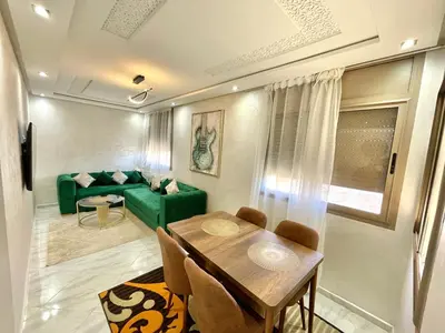 a living room with a table and a green couch at A2 Luxe Moderne et Confort, 7 min du Stade Moulay Abdellah in Temara