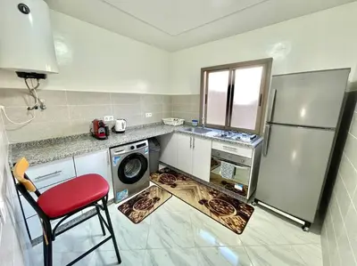 a kitchen with a refrigerator and a red chair at A2 Luxe Moderne et Confort, 7 min du Stade Moulay Abdellah in Temara