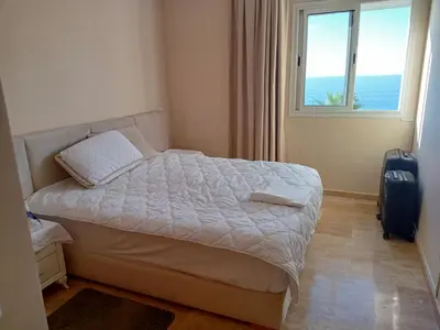 a bedroom with a bed with a window and a suitcase at Appart 3p vue sur mer in Rabat