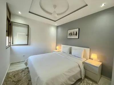 a bedroom with a large white bed with two lamps at A3 Luxe and Cosy Apartement, 7 min du Stade Moulay Abdellah in Temara