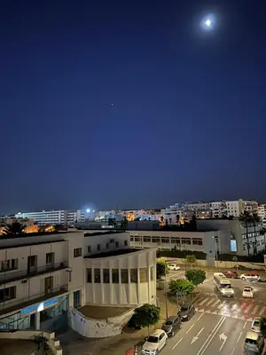 a view of a city at night with the moon at SUITOUISS - Agdal 1 - Appartement à 2 minutes de la gare de train TGV Rabat in Rabat
