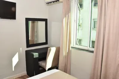 a bedroom with a desk and a mirror and a window at Cadé Hotel in Casablanca