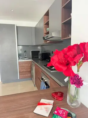 a vase with red flowers on a table in a kitchen at Appartement CFC - Aeria mall in Casablanca