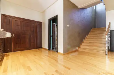 an empty room with a staircase and wooden doors at Luxury villa Bouskoura Pearl in Casablanca