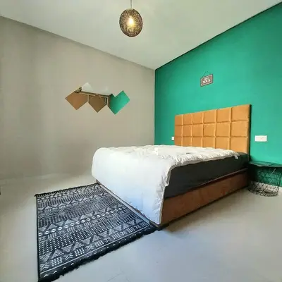 a bedroom with a bed and a green wall at Airport mohamed 5 break apartments in Derroua