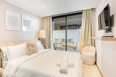 a white bedroom with a large bed and a table at TTHOLIDAYS Cosy Apartment Casablanca City Center in Casablanca