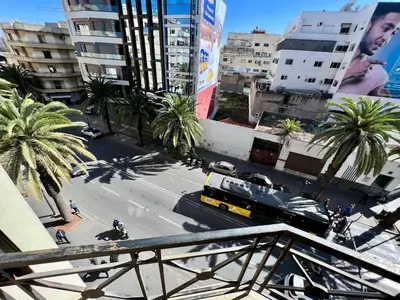 a bus driving down a city street with palm trees at Maarif , Cosy 2 Chambres, Parking wifi Netflix Gratuit in Casablanca
