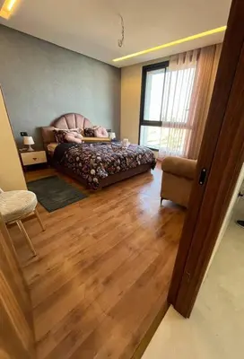 a bedroom with a bed and a chair and a window at Luxury flat at Casa Finance city in Casablanca