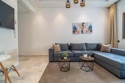 a living room with a blue couch and two tables at AeroHarmony in Nouaceur
