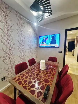 a dining room with a table with chairs and a tv at modern apartment opposite to HASSAN2 MOSQUE & FAIR international casablanca , near downtwn, with side SEA view with sports machines with free underground GARAGE prohibited for unmarried couples of Arab original apartment too QUIET in Casablanca