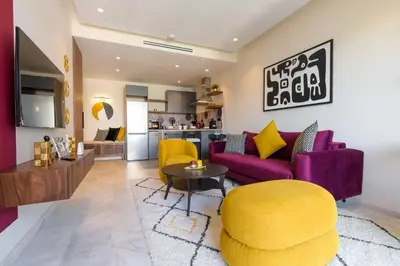 a living room with a purple couch and yellow chairs at Appartement luxueux et lumineux Maarif Casablanca in Casablanca