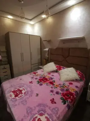 a bedroom with a pink bed with flowers on it at Charmant appartement 15 minutes de la plage in Mohammedia