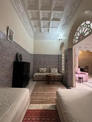 a bedroom with two beds and a couch and a table at Riad Blue Garden in Rabat
