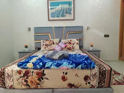 a bed with a blue blanket and pillows on it at Rooms in shared apartment close to CMN-Airport in Dah Hammou Ben Cheïkh