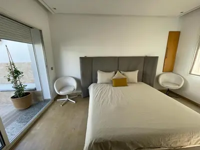 a bedroom with a large bed and two chairs at Central, terrasse, confortable - Bleue résidence in Casablanca