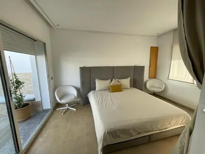 a bedroom with a bed and two chairs in it at Central, terrasse, confortable - Bleue résidence in Casablanca