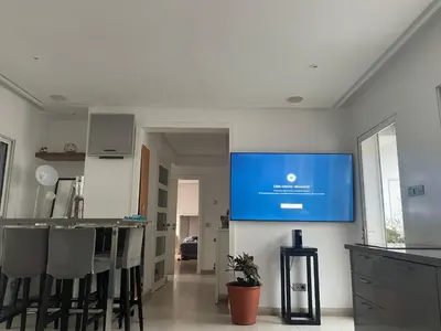 a tv hanging on a wall in a kitchen with chairs at Central, terrasse, confortable - Bleue résidence in Casablanca