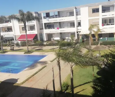 an apartment complex with a swimming pool and palm trees at Marbella beach appart de standing in Mansouria