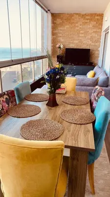 a long wooden table with chairs and a couch at Bel appartement pieds sur mer in Casablanca