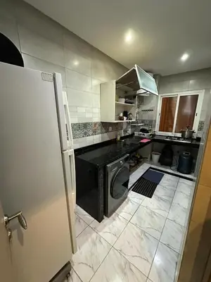 a kitchen with a black counter and a refrigerator at Apparemment TAMARIS in Dar Bouazza