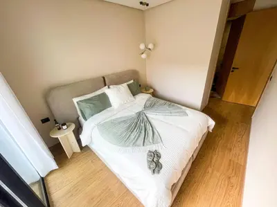 a bedroom with a bed with white sheets and green pillows at Modern Studio with Balcony & Parking Les Princesses 204 in Casablanca