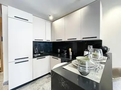 a kitchen with white cabinets and a black counter top at Modern Studio with Balcony & Parking Les Princesses 204 in Casablanca