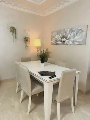a white dining room table with chairs and a painting at Lilias Appart - 2 Mars in Casablanca