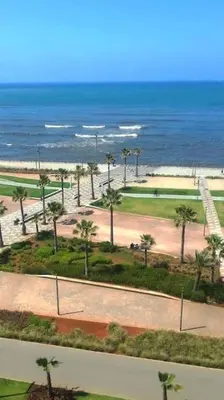 a view of a park with palm trees and the ocean at Appartement moderne vue sur mer in Casablanca